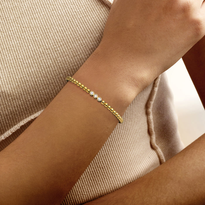 Gold beaded stretch bracelet with small round diamonds along the front row on wrist