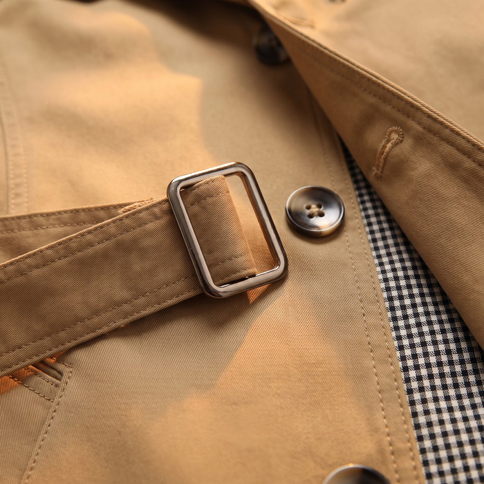 Close-up of the buckled waist tab and houndstooth check lining on the camel car coat