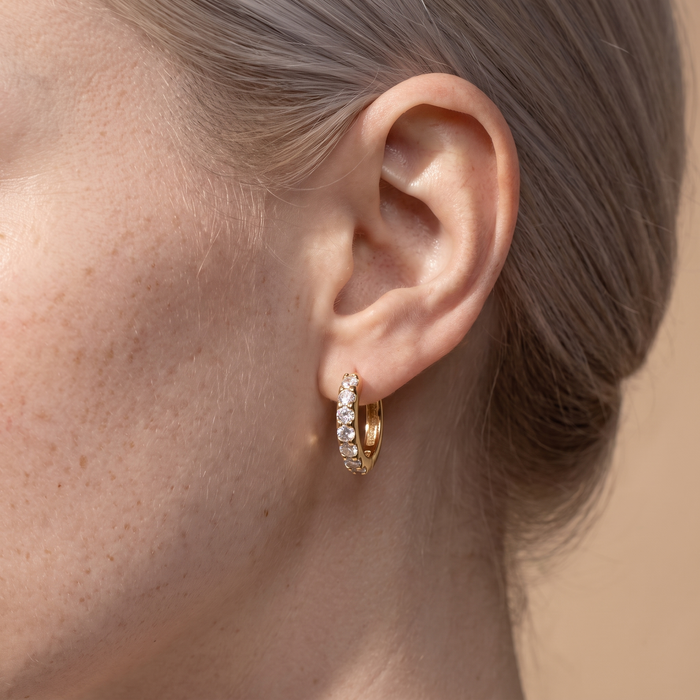 Close-up of the Aava gold-plated stone mini hoop earring worn on the ear
