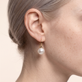 Close-up of the Alina gold-plated pearl hook earring worn on the ear