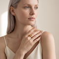 Model wearing the Ansa gold-plated sculptural hug ring on her index finger