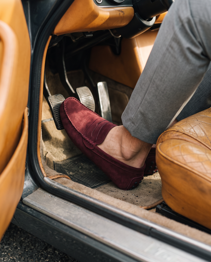 Burgundy driving loafers in a classic car footwell