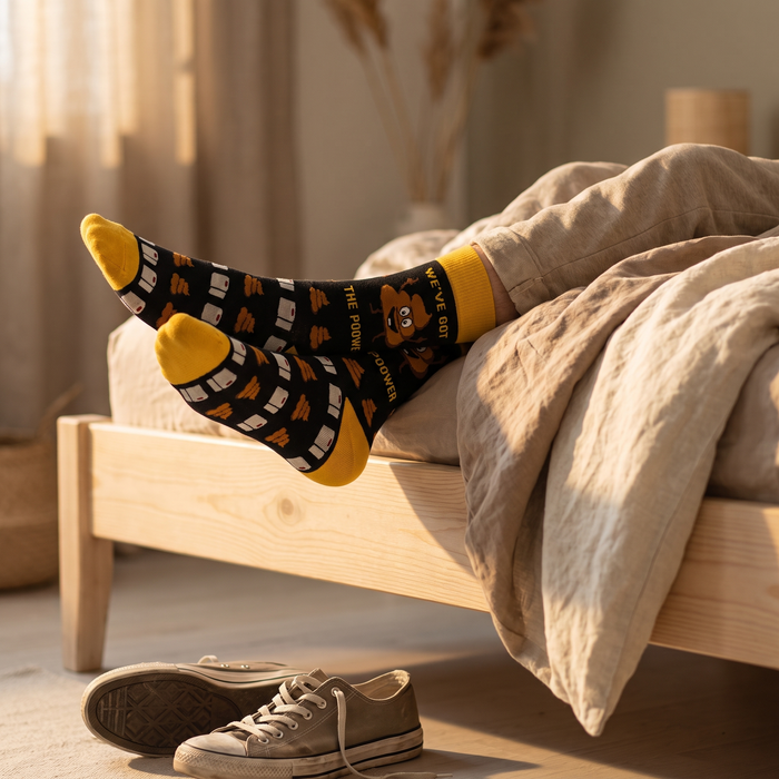 Feet in animal-print mid-calf socks resting on a wooden bed frame