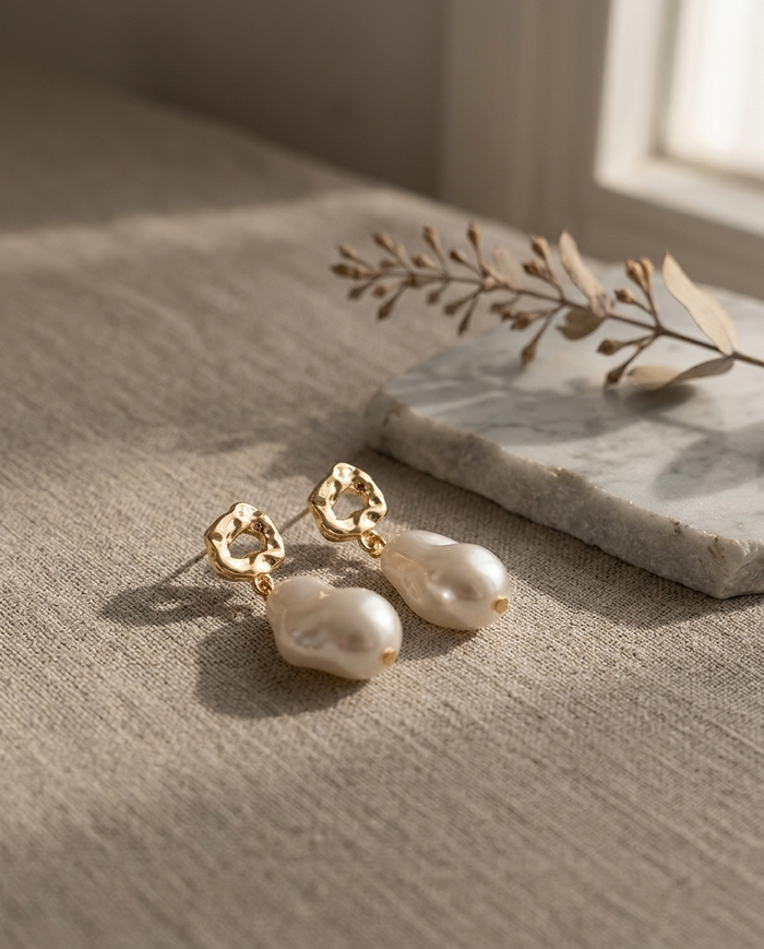 Baroque pearl drop earrings styled on linen