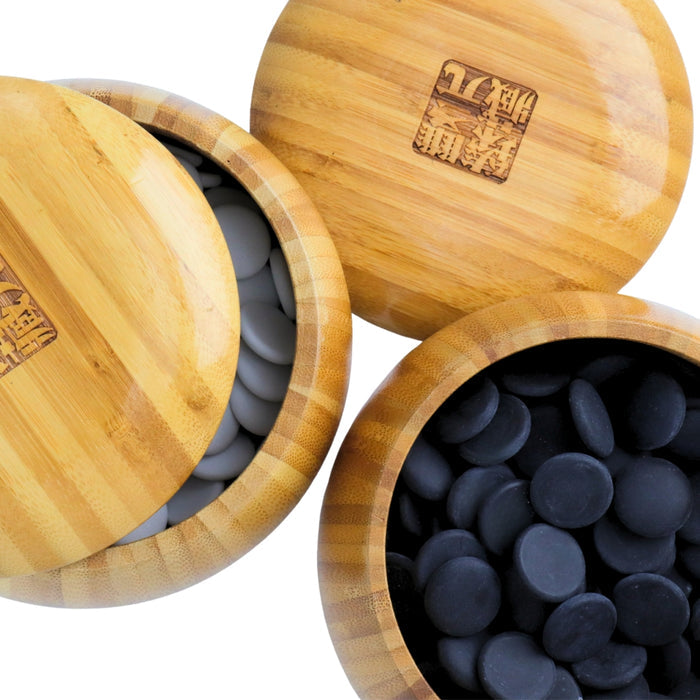 Top view of Go Bowls & Stones Set with lids lifted off 2 bamboo bowls showing black and white ceramic go stones