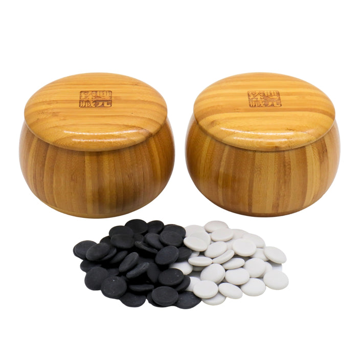 Go Bowls & Stones Set with black and white ceramic go stones laying in front of closed bamboo bowls