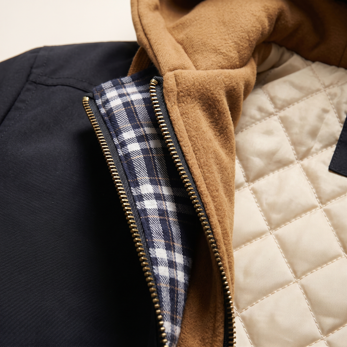 Close-up of the front placket showing the check facing, brass zip and diamond-quilted lining