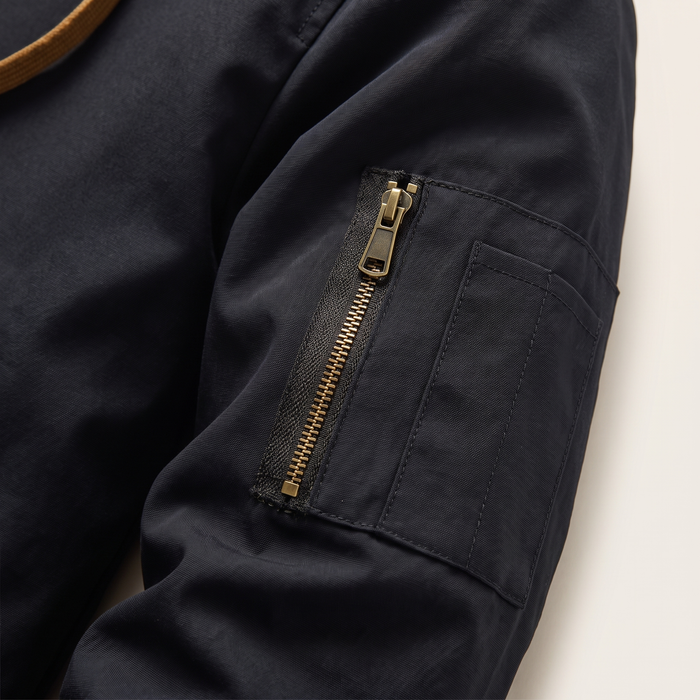 Sleeve detail of the quilted hooded bomber jacket showing the zipped utility pocket
