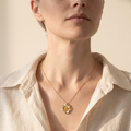 Model wearing the Iida gold-plated flower pendant necklace at the collarbone