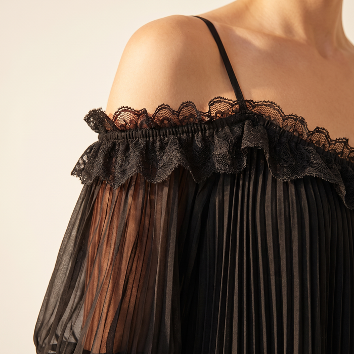 Close-up of the Ilta dress fabric, showing the fine chiffon pleating, sheer sleeve and black lace trim