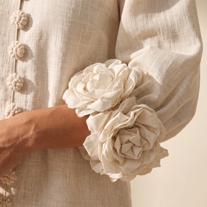 Close-up of the Kaisla dress fabric, showing the slubby cotton-linen weave, knot buttons and 3D fabric flower