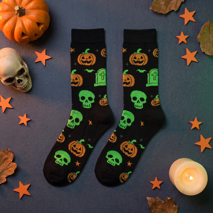 Kalmisto black Halloween crew socks with orange pumpkins and green skulls, flat lay with a carved pumpkin, skull and stars