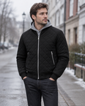 Man wearing the black padded winter jacket zipped over a grey hoodie on a winter street
