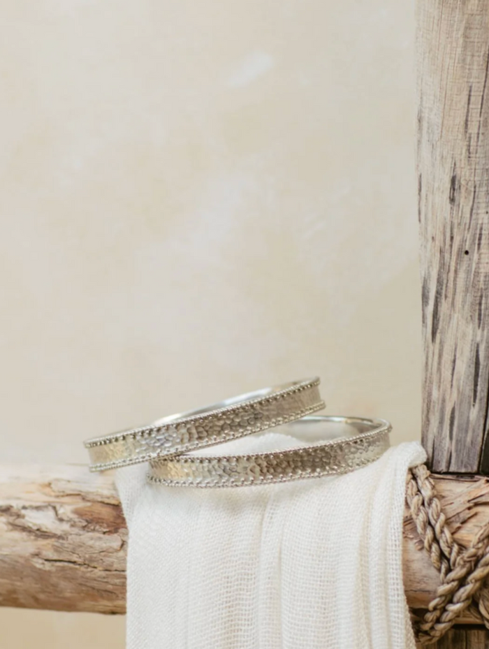 White Brass bangles on a wooden surface with a neutral background