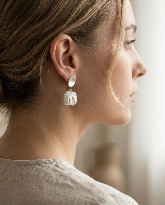 Silver square pearl drop earring worn on the ear