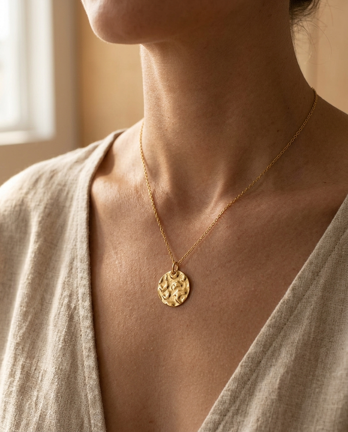 Round hammered disc necklace worn at the collarbone