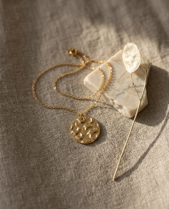 Round hammered disc necklace styled on linen with marble