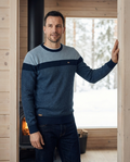 Blue colour-block jumper worn in a Nordic timber home interior